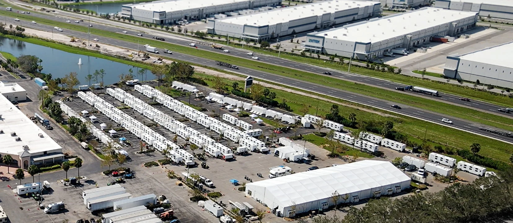 An aerial view of DRG logistics base camp deployed in a large parking lot next to a freeway after Hurricane Millton, 2024.