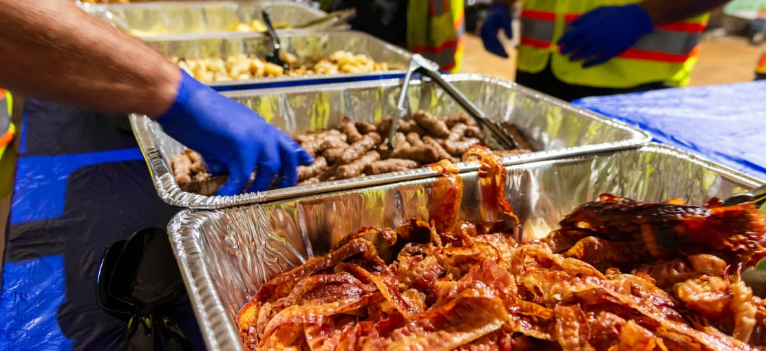 A DRG food service employee prepares hot food inside a dining tent.