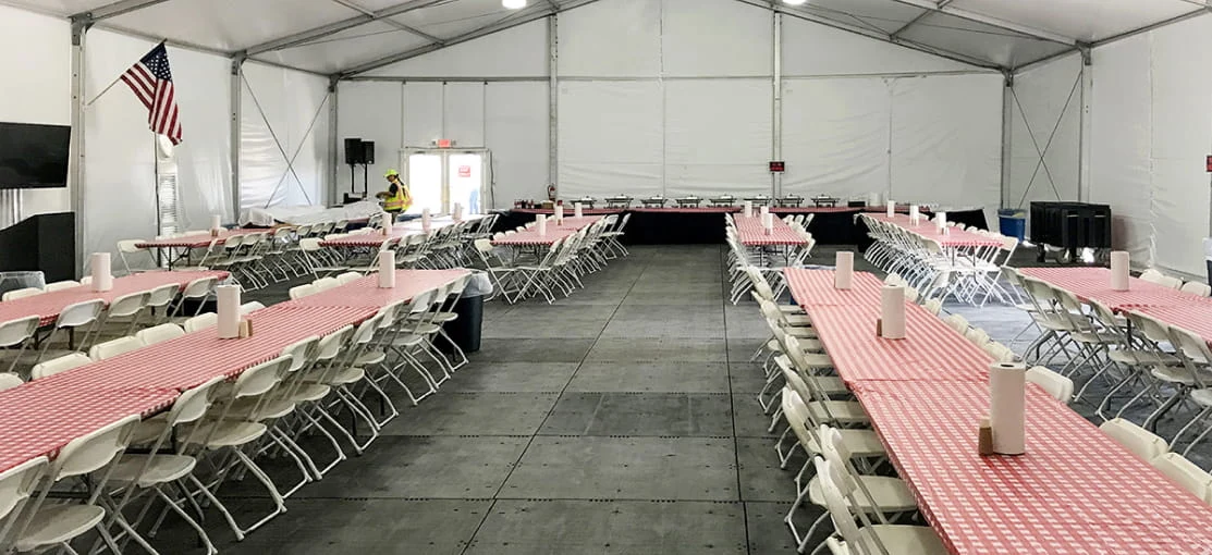 Long rows of dining tables inside a dining tent.