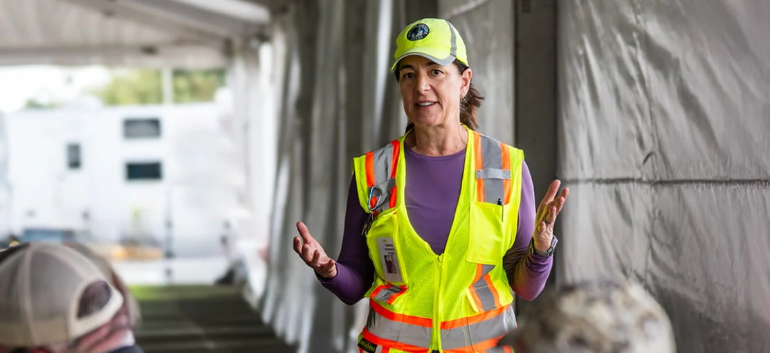 A DRG employee speaks to other employees at a base camp.