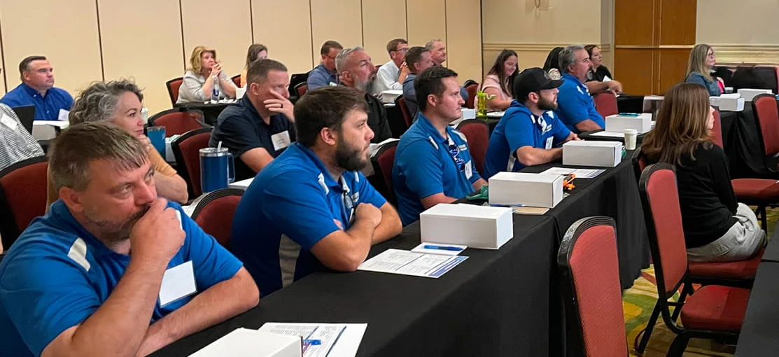 DRG employees listen to a speaker at a training center.