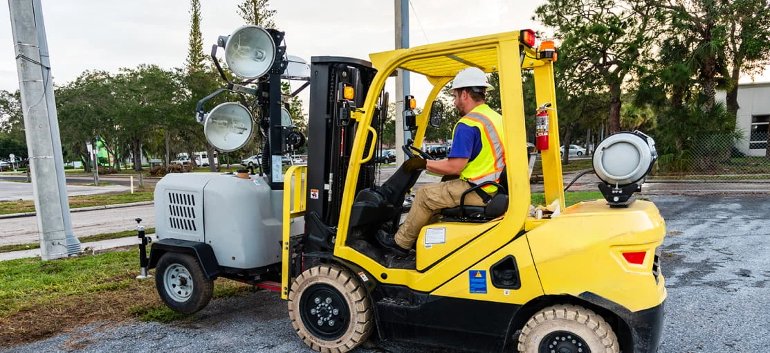 An employee on a DRG forklift moves utility equipment into place on a disaster site.