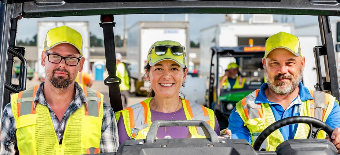 Three DRG employees drive a vehicle on a base camp.