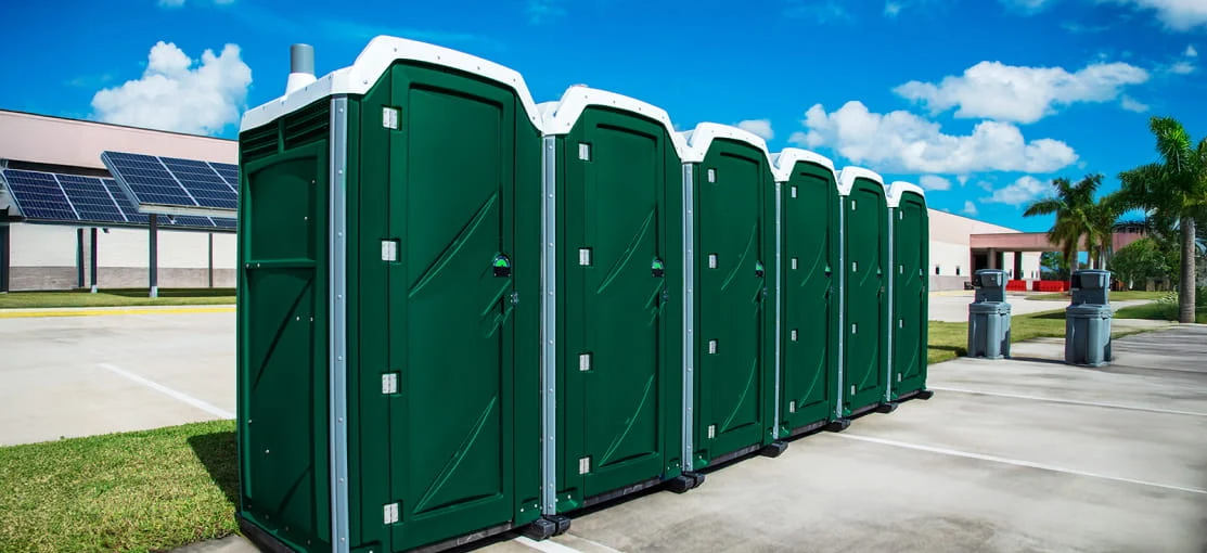 A row of green mobile restrooms.