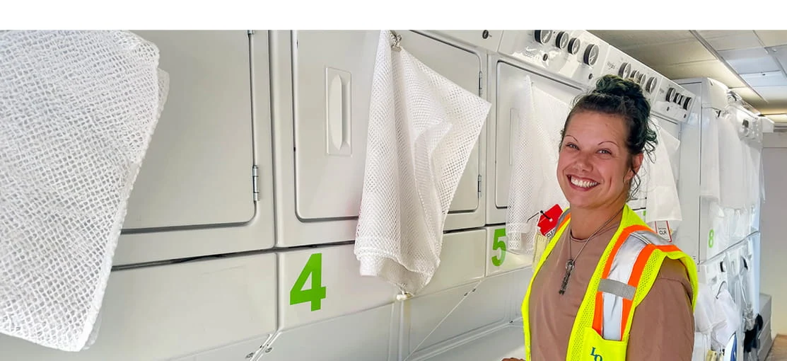 A smiling DRG employee inside a mobile laundry trailer.