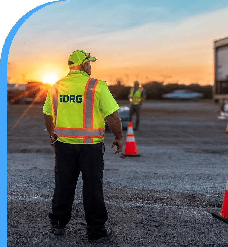 A DRG employee in a yellow vest surveys base camp.