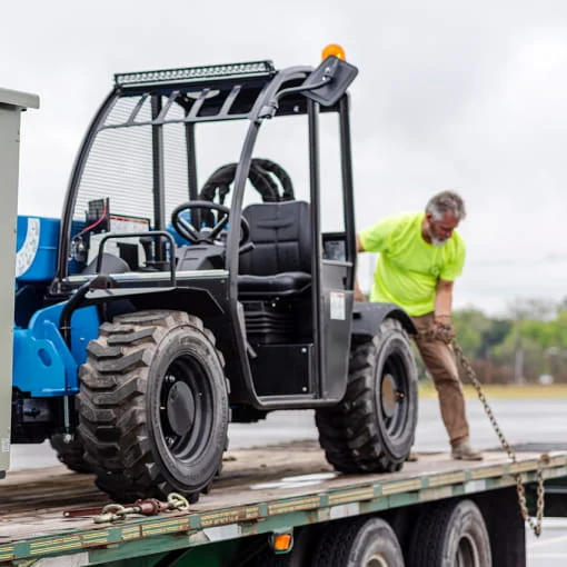 A DRG employee secures an all-terrain vehicle on transport trailer.