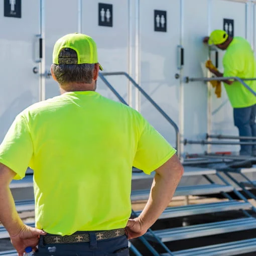 DRG employees in yellow T-shirts maintain a mobile restroom trailer.