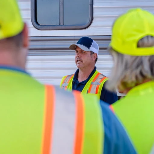 A small group of DRG employees gather around a mobile command center for a meeting.