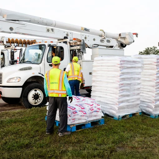 DRG catering services employees receive an ice delivery at a disaster base camp.